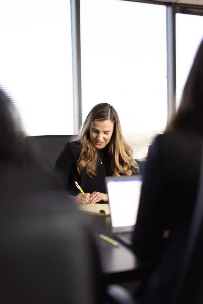A J. Alexander Law Firm attorney taking notes at a conference table during a case review