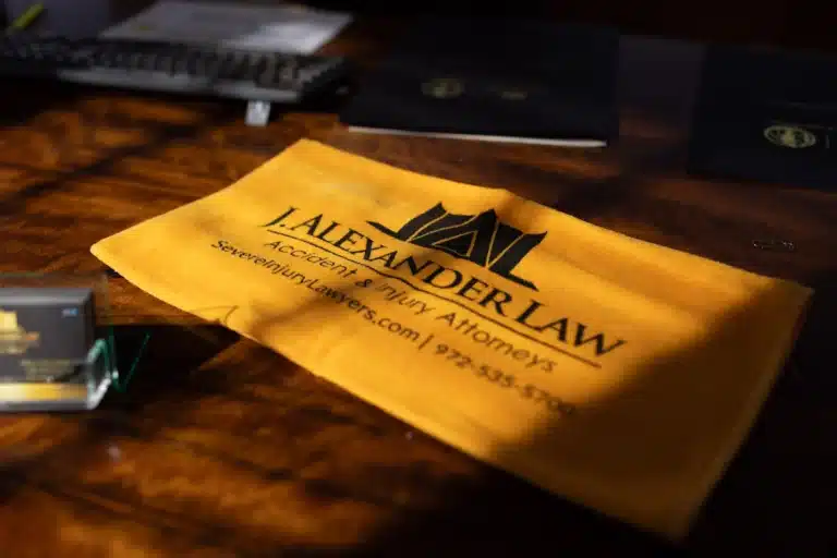 A gold J. Alexander Law folder lying on a dark wood desk