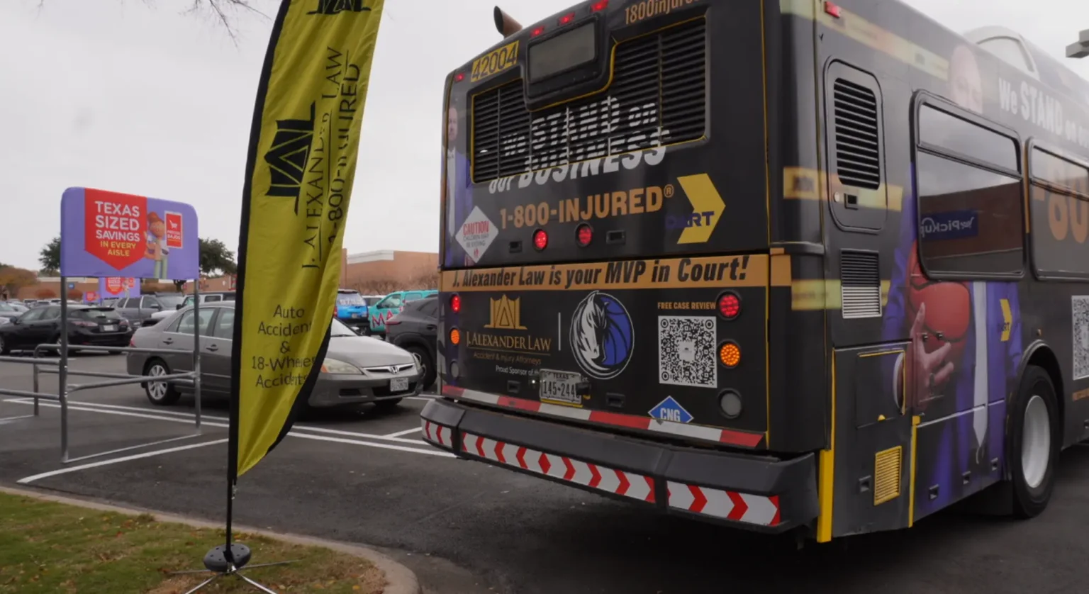 The back of a DART bus wrapped in a J. Alexander Law ad reading We Stand on our Business, 1-800-INJURED, and J. Alexander Law is your MVP in Court