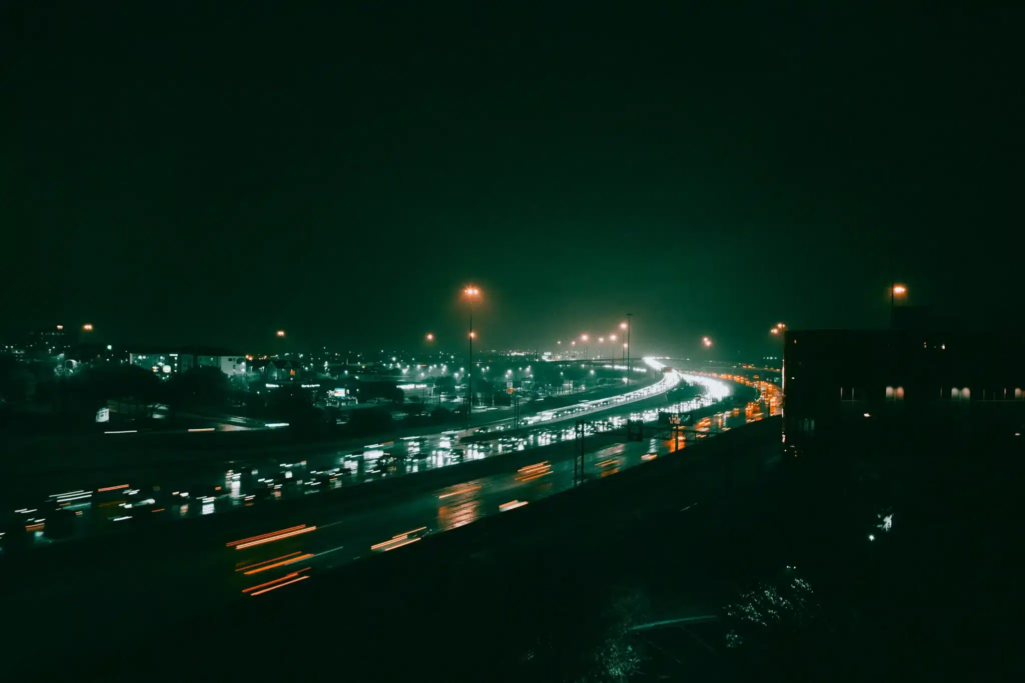 Multi-lane highway at night with dense traffic and headlight trails