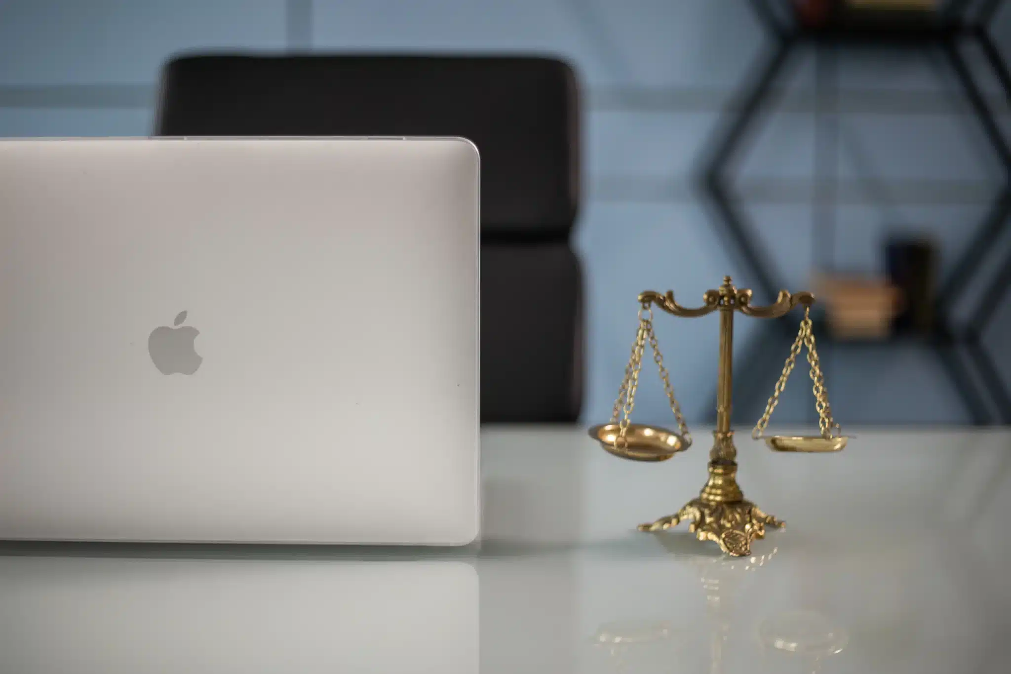 Scales of justice on a desk beside a laptop