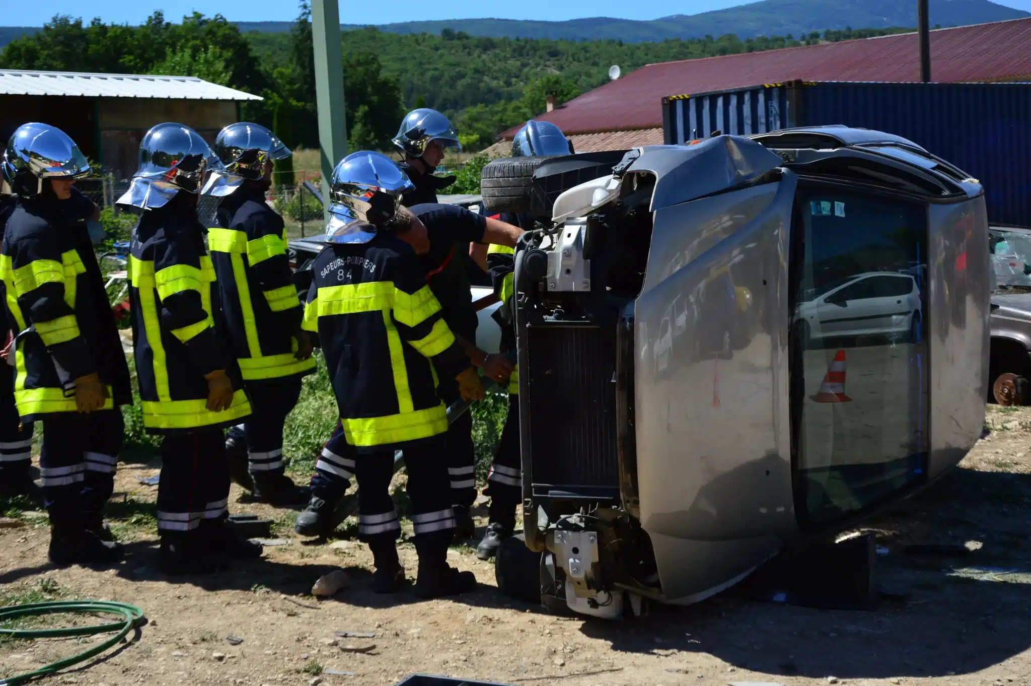 Firefighters working a crashed, overturned car at the roadside