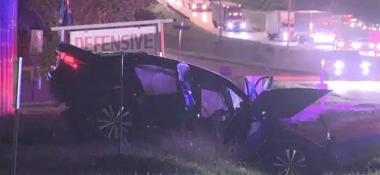 A destroyed SUV beside the highway after a nighttime rollover on I 35E