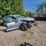 The client's silver sedan with a crushed front end, a shattered windshield, and a front door open after the Rockwall County crash