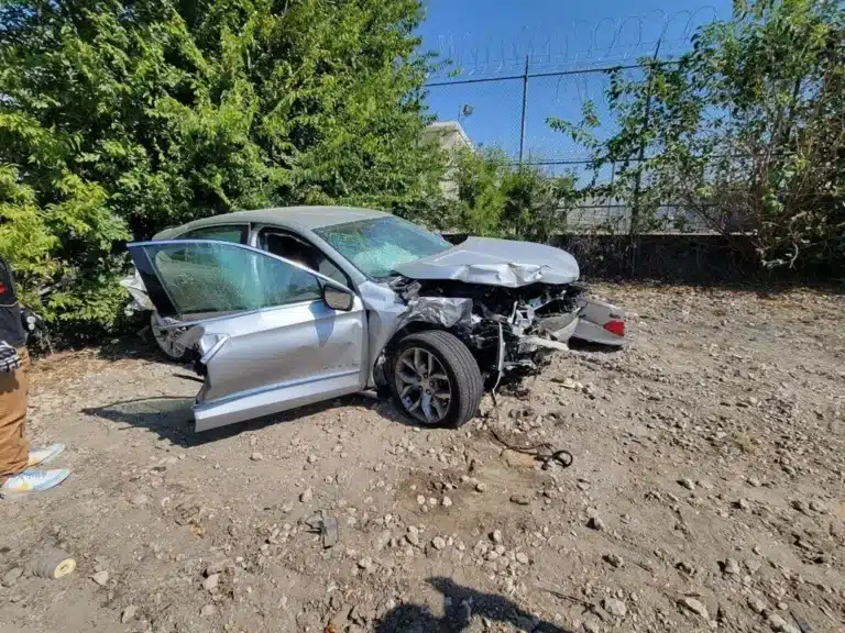 The client's silver sedan with a crushed front end, a shattered windshield, and a front door open after the Rockwall County crash