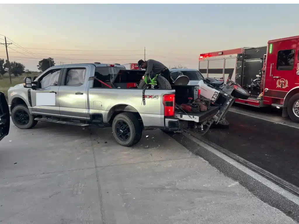 A company pickup stopped on FM 1788 near Midland with its overturned trailer behind it and a fire engine alongside