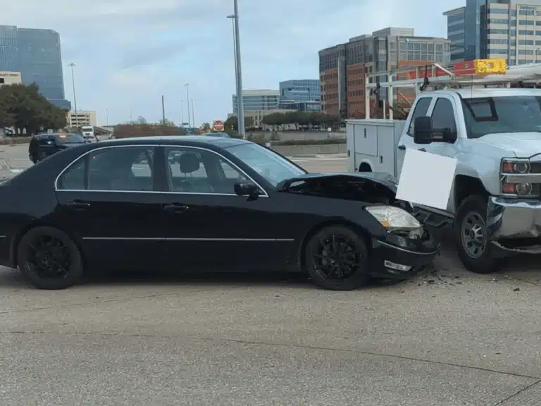 Damaged Lexus after the company truck left turn crash at Legacy Drive and Dallas Parkway in Plano, stopped nose to nose with the white Chevrolet 3500 HD pickup