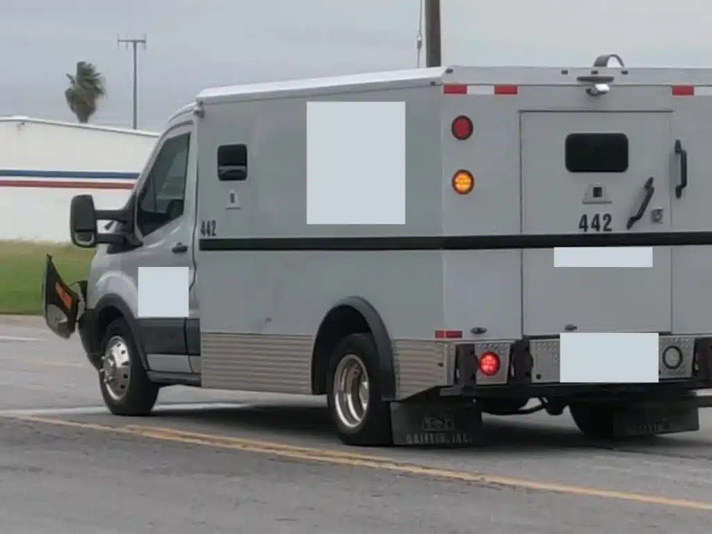 Side and rear view of the white Ford Transit armored truck, unit 442, stopped on the roadway after the collision