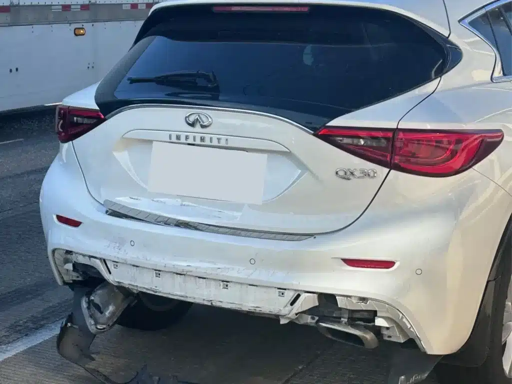 Rear bumper cover torn loose and hanging from the back of the client's white SUV after the crash on U.S. 75