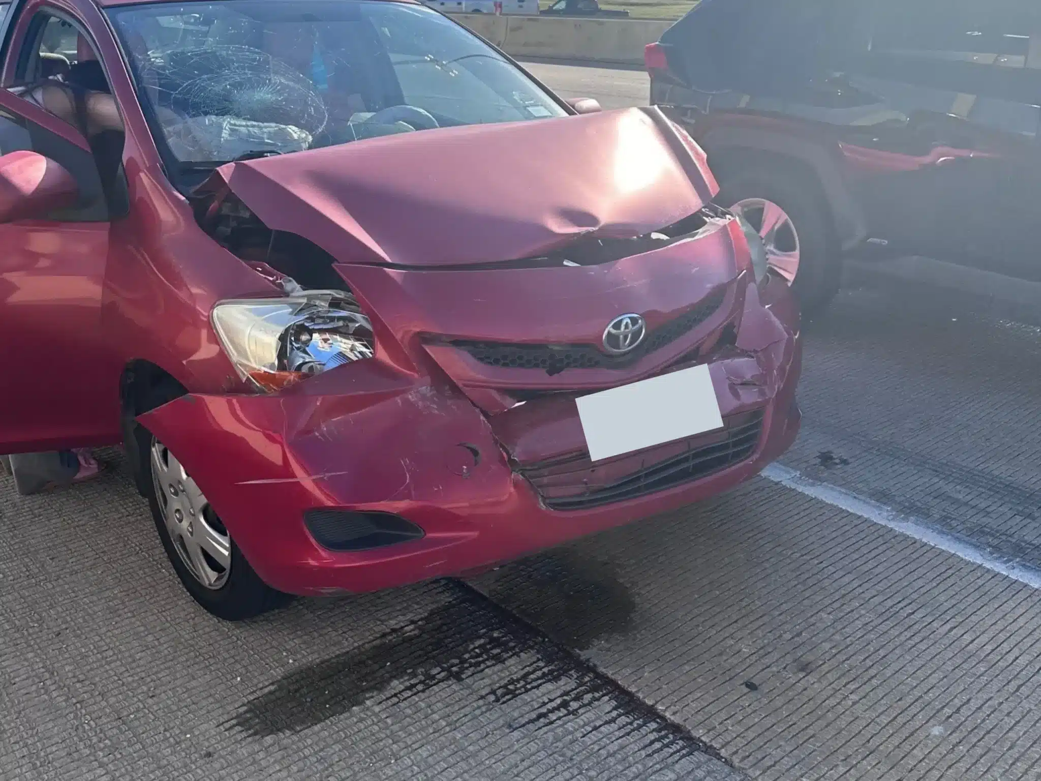 The striking red sedan with a crumpled hood, a front bumper pushed inward, and a cracked windshield
