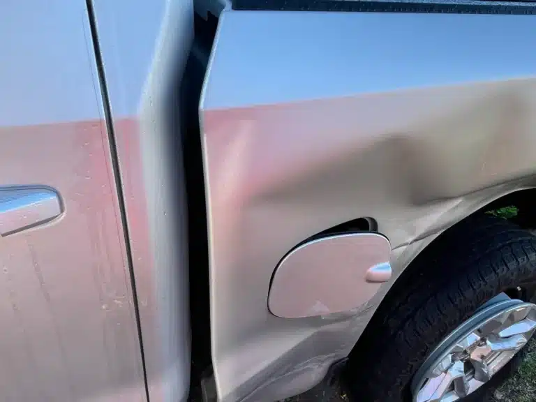 A pushed in dent across the bed side panel beside the fuel door of the client’s Chevrolet Silverado after the Pasadena crash