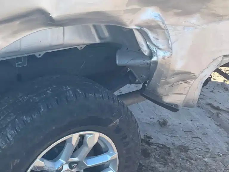 Crumpled and torn bodywork at the rear wheel opening of the client's Chevrolet Silverado after the Pasadena crash