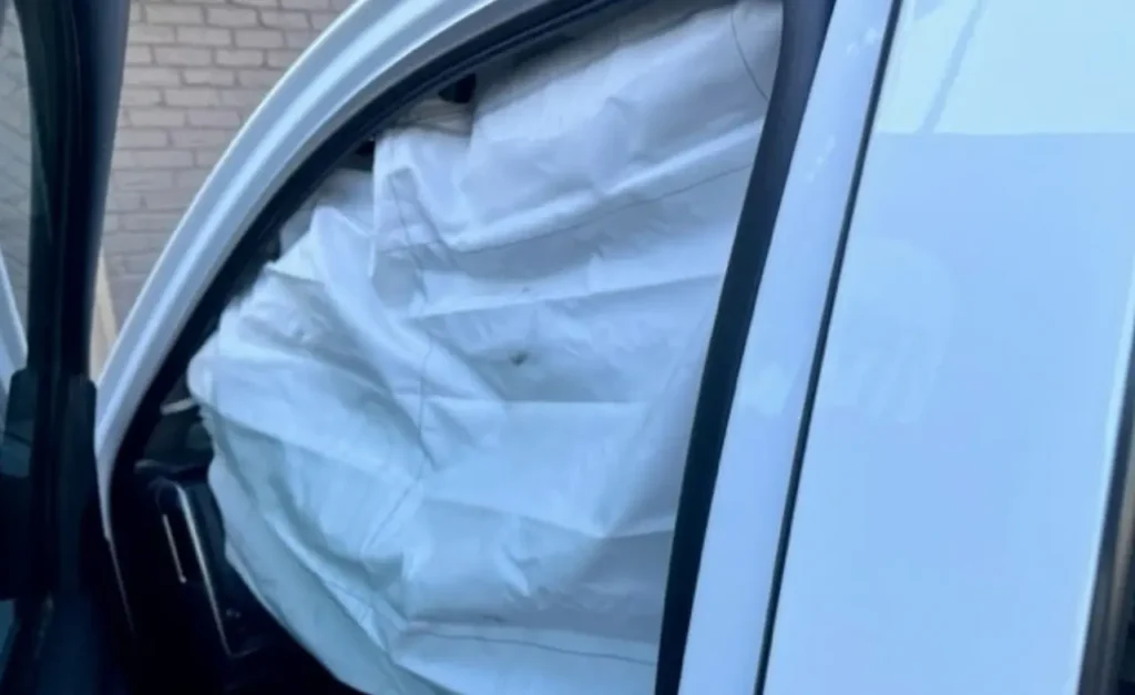 A deployed side curtain airbag hanging down inside the pickup&rsquo;s cab beside an open door