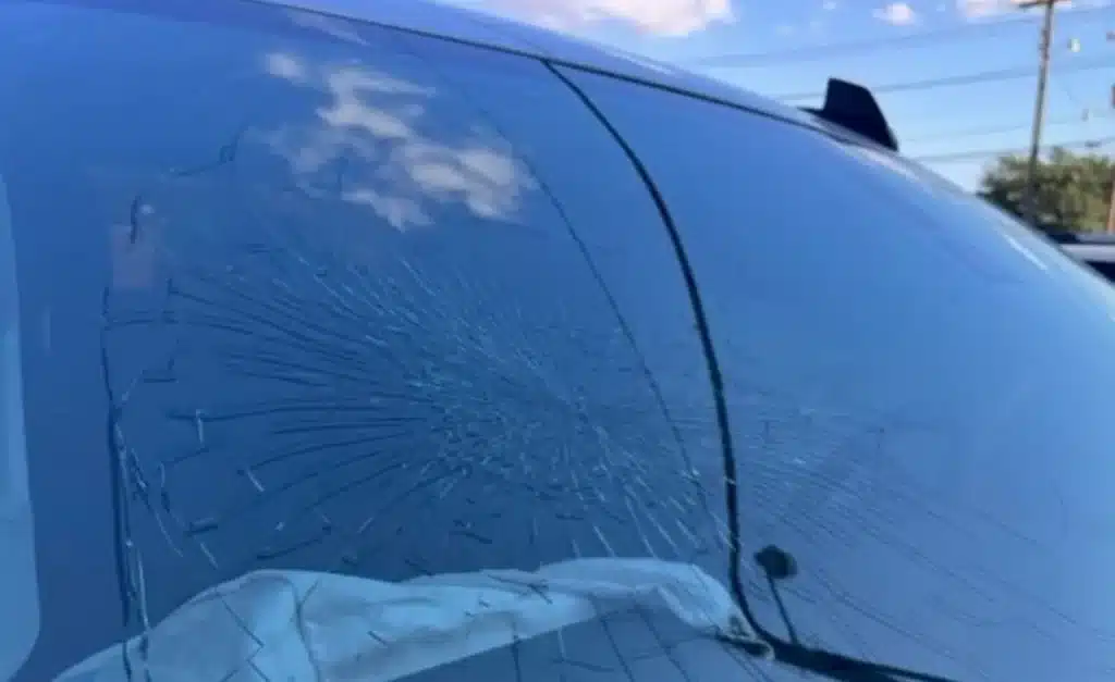 The pickup&rsquo;s windshield with cracks spreading across the glass in a starburst