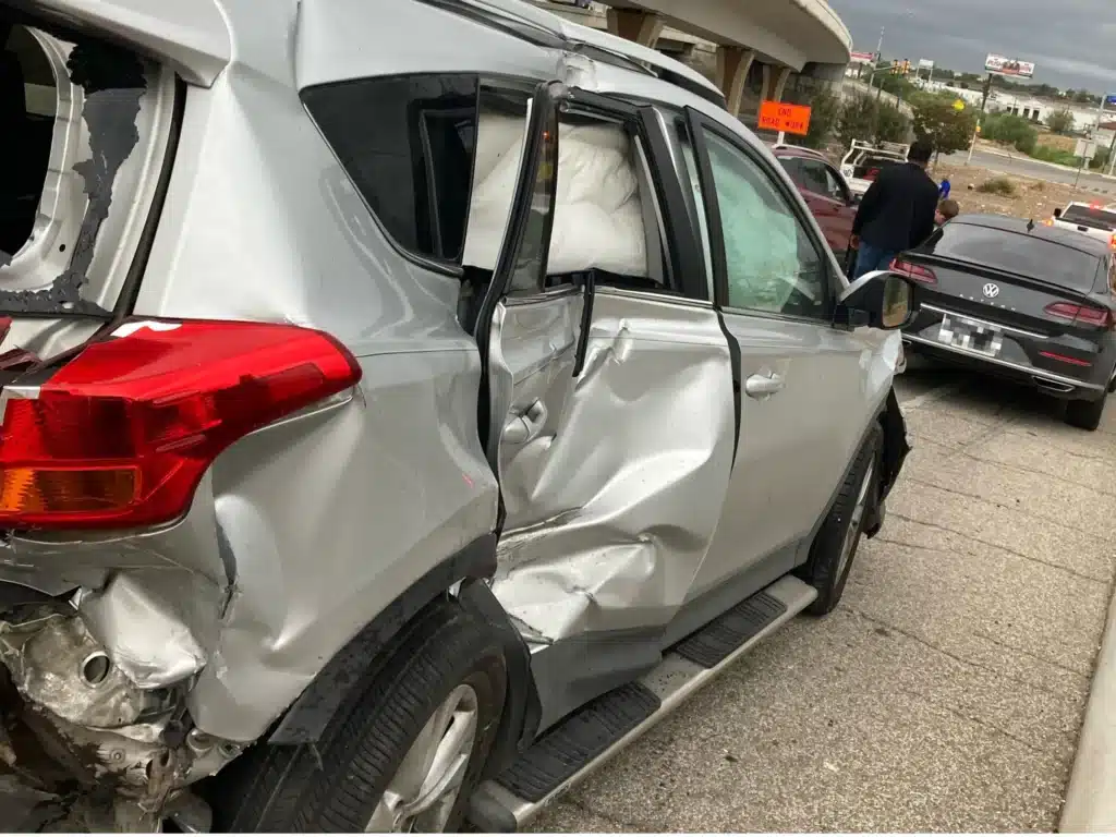 Right side of the RAV4 with the rear door buckled inward, the rear quarter crushed and the side curtain airbag hanging behind the windows