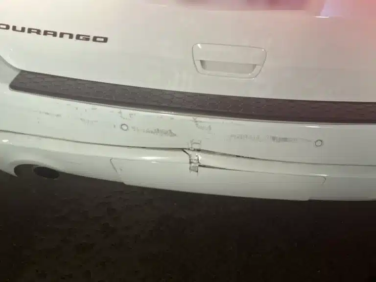 Parachoques trasero del SUV blanco de nuestra clienta despu&eacute;s de que un conductor ebrio lo chocara por detr&aacute;s en Midland, con la cubierta del parachoques partida y hundida en el centro