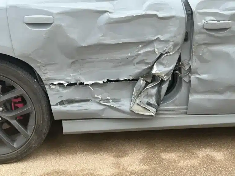 Vista cercana de las puertas de pasajeros delantera y trasera del sed&aacute;n, hundidas hacia adentro, con la puerta trasera rasgada en la parte inferior