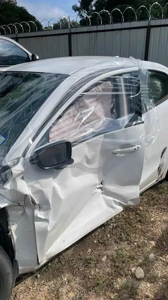 El lado del conductor del sed&aacute;n de nuestra clienta, con la salpicadera delantera y la puerta hundidas y pl&aacute;stico pegado con cinta sobre las ventanas rotas