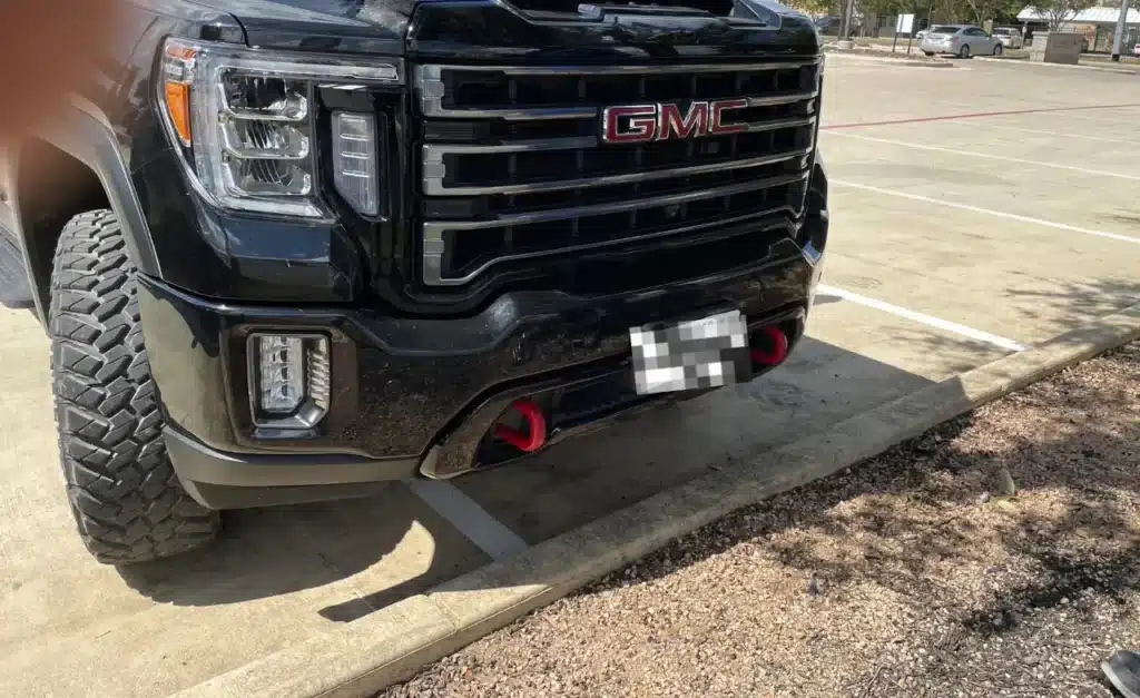 Front of the black pickup that hit the RAV4, parked in the same lot after the crash; its plate is pixelated
